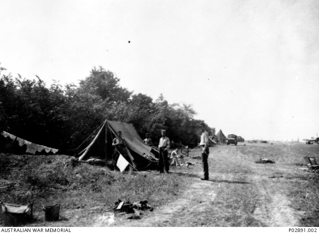 A tent and washing line beside a protective dugout; squadron members and a Typhoon at B5.