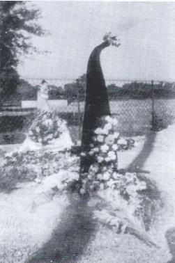 An early photograph of George’s grave, with flowers and a propeller part behind them.